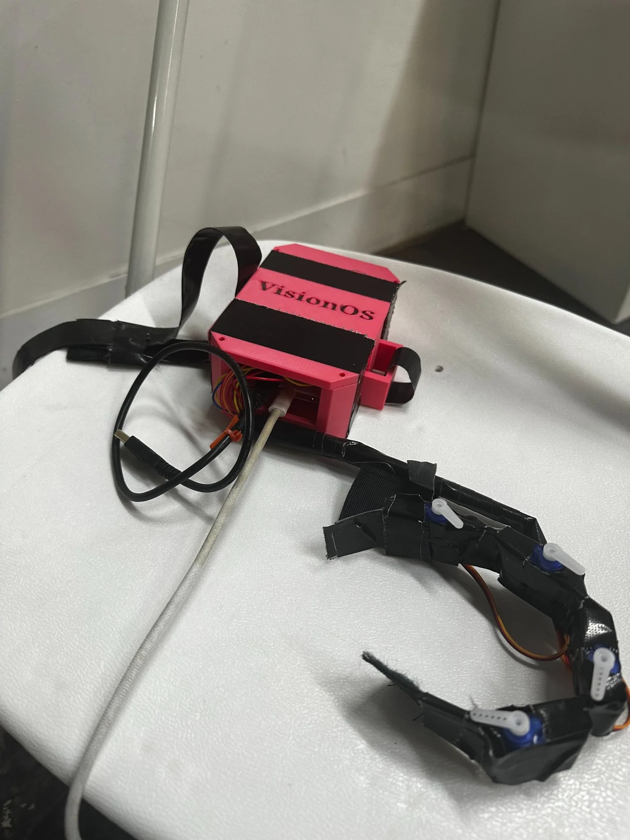 Another angle of the connected VisionOS prototype, showing the pink enclosure alongside the wearable actuator assembly.